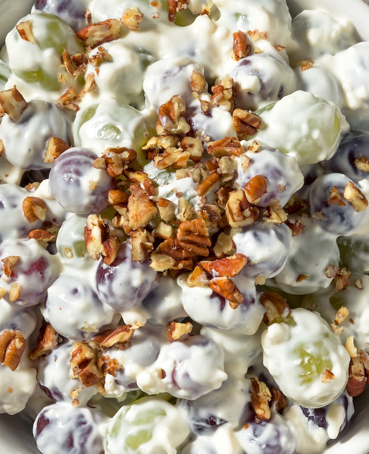 Yummy Grape Salad made with a mixture of cream cheese, greek yogurt and sugar! A super quick and easy make ahead party food idea. This sweet side dish is great for pool parties, potlucks, family gatherings, holidays, parties and more. Top it with chopped pecans for the ultimate crowd pleasing food. 