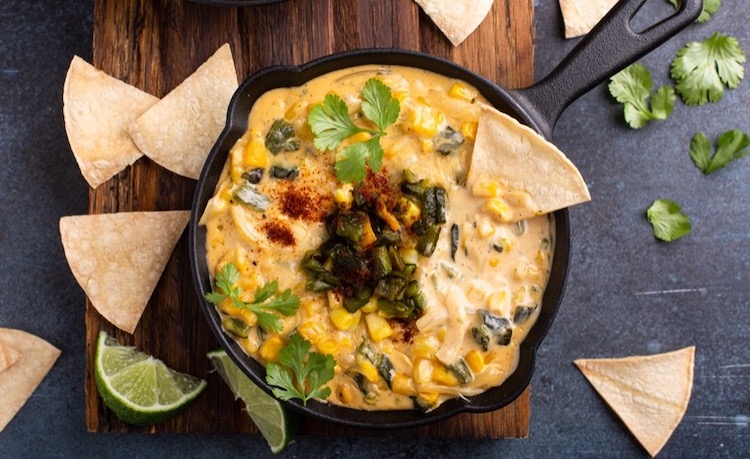 Cheesy Poblano Corn Dip is a yummy chip dip for parties made with cream cheese, sour cream, poblano peppers, and corn in a cast iron skillet in your oven. Serve warm with tortilla chips.