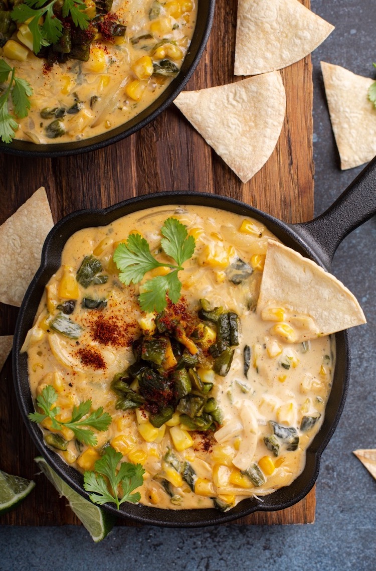 Easy Party Dip Recipe made in a cast iron skillet with cream cheese, sour cream, cheddar, poblanos and corn! Serve at your next gathering with tortilla chips for the most addicting party food. A great way to impress your guests!